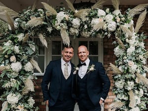 John George and his brother Darren under a flower arch