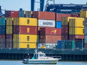 Shipping containers stacked on a dock, with a small boat in the foreground