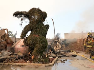 A firefighter walks past a charred bunny sculpture and debris