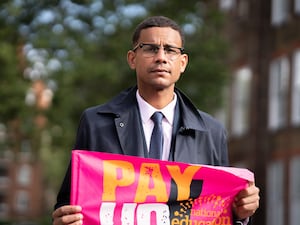 Daniel Kebede, general secretary of the National Education Union, holding a strike banner