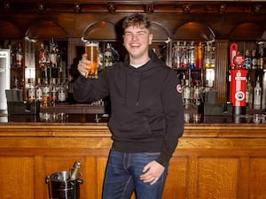 James Clarkson holding a pint in front of a bar