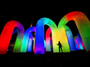 A person standing in front of large inflatable arches, which are multicoloured