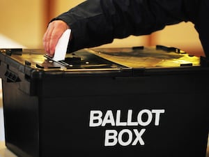 A voter puts a ballot paper in a ballot box at a polling station