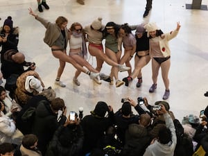 Crowds gathered around a group of women dressed without their trousers at Waterloo Station