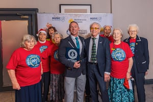 Members of the choir pose with Carl Saville (adjudicator for Guinness World Records) and Tony Christie