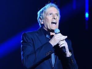 Michael Bolton holding a microphone and singing on stage