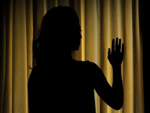 The silhouette of a woman next to closed curtains