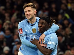 Manchester City’s Jeremy Doku celebrates scoring the opening goal with a jumping James McAtee