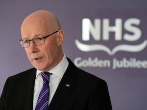 John Swinney speaking in front of an NHS Golden Jubilee sign