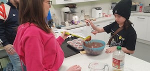 Rebecca Bunger helps Layla to spoon out the red velvet cupcakes