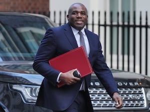 Foreign Secretary David Lammy walks along a street carrying a red folder