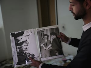 A man showing an album of Assad family photos