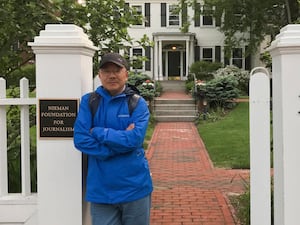 A man in a blue jacket stands by white entrance gates