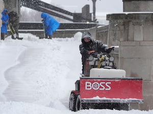 Workers clear snow from a walkway