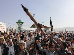 Houthi supporters carrying a mock rocket