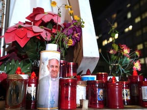 Candles are left at the foot of a marble statue of late Pope John Paul II outside the Agostino Gemelli Polyclinic in Rome where Pope Francis is being treated for pneumonia