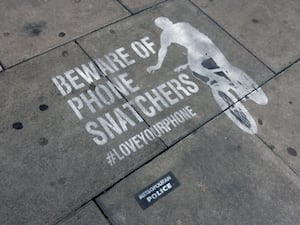 A Metropolitan Police 'Beware of Phone Snatchers' warning stencilled on a London pavement