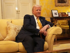 Donald Trump seated on a sofa in an opulent room