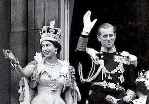 Queen Elizabeth II, wearing the Imperial State Crown, and the Duke of Edinburgh, in the uniform of Admiral of the Fleet, waving from the balcony of Buckingham Palace after the Queen's Coronation. 