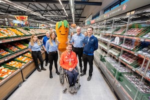 Nick Cummins is given a tour of the store by members of staff and the Aldi mascot Kevin the Carrot. Photo: Richard Grange