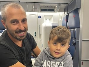 A man sits on a plane with his son on his knee