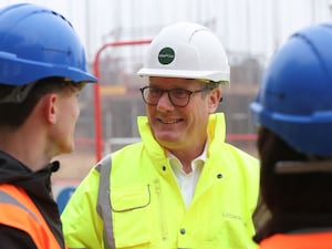 Sir Keir Starmer in hard hat and hi-vis talking to builders