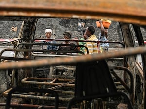 Residents walk by charred vehicles in Goma