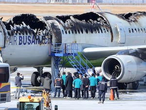 Firefighters and other officials visit the site where an Air Busan airplane caught fire at Gimhae International Airport