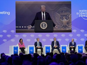 Donald Trump on a large screen as people sit below