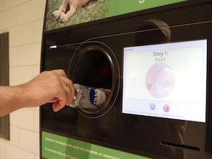 Someone placing a bottle in a deposit return scheme