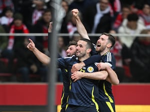 John McGinn, front, celebrates with two Scotland team-mates