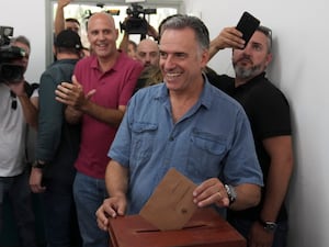 Yamandu Orsi smiles while placing his vote in a ballot box