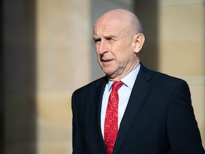 John Healey in the street wearing a suit and a red tie