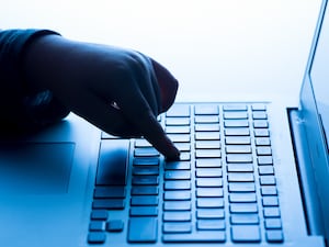 A child’s hand pressing a key of a laptop keyboard