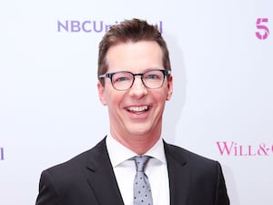 A close-up of Sean Hayes, smiling and wearing glasses