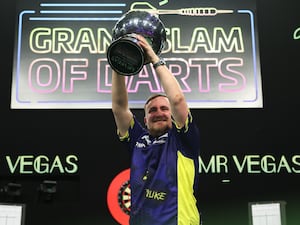 Luke Littler holds up the Grand Slam of Darts trophy