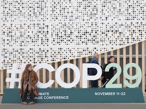 An attendee sits on a sign for the Cop29 UN Climate Summit