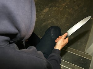 A man in a hoodie holding a knife