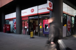 A person walks past a branch of the Post Office