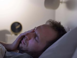 A man lying in bed, looking tired