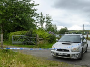 Police tape around a car and entrance to a property