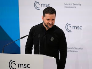 Volodymyr Zelensky smiling while at a lectern