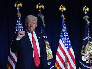 Donald Trump holding up his fist in front of some flags