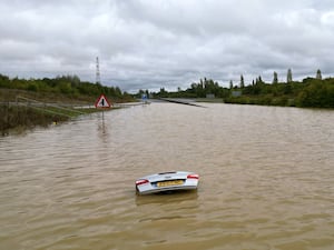 The open boot of a car is visible above the water where the vehicle is submerged in flood water on a421 in Marston Moretaine, Bedfordshire.