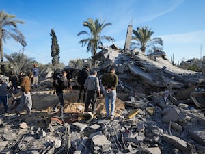 People walking amongst rubbled and the remains of homes