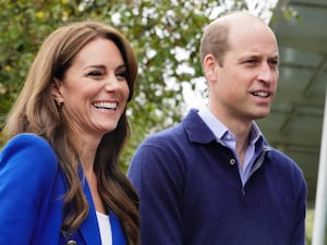 Kate, in a blue blazer, and William, in a blue sweater. They are both similing.