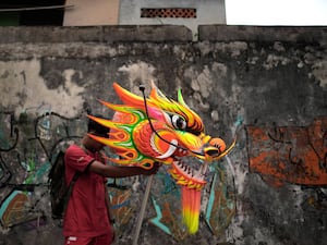 A member of a dance troupe holds the head of a dragon puppet