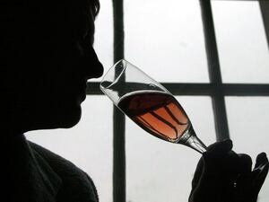 A stock image of a silhouette of a man drinking rose wine from a champagne flute