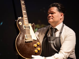 An art handler holding Jeff Beck's 1954 Gibson Les Paul Oxblood guitar