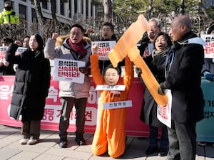 A protester wearing a mask of impeached South Korean President Yoon Suk Yeol attends with his fellow protesters during a rally calling for him to step down in front of the Constitutional Court in Seoul